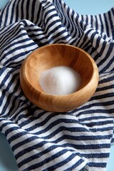 Wooden bowl of sugar on a striped kitchen cloth, rustic scene