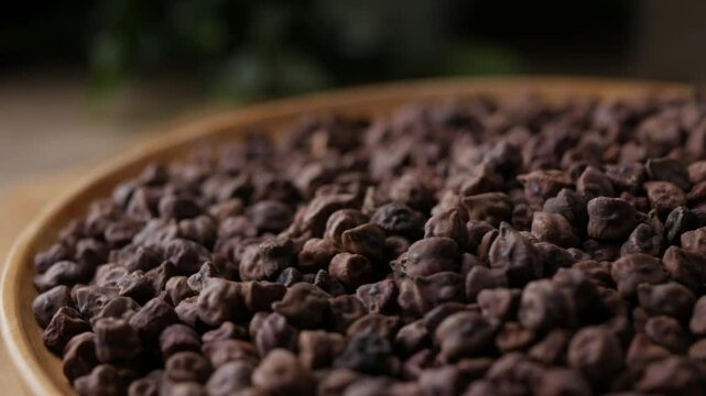 Raw Dark Brown Chickpeas (Kala Chana) on a rustic wooden table. Dry Balck chickpea (ceci neri) background close up. 