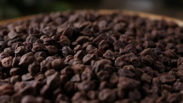Raw Dark Brown Chickpeas (Kala Chana) on a rustic wooden table. Dry Balck chickpea (ceci neri) background close up. 