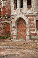 Gothic brick arch of abandoned castle facade sealed with weathered masonry shows historic decay