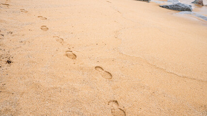 Footprints in the sand: tranquil beach scene with ocean waves and rocky shoreline