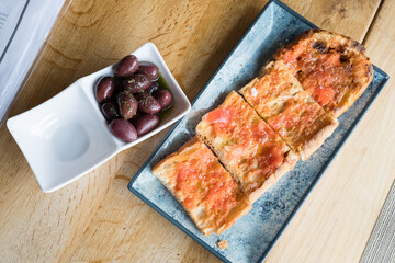 Traditional spanish pan con tomate with marinated olives on wooden table