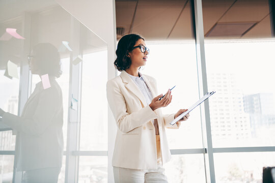 Charming businesswoman holding clipboard and speaking during a meeting in a modern corporate office