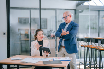 Business professionals collaborating during a meeting in a contemporary office, engaging with a tablet while analyzing financial charts and data to drive strategic decisions