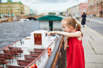 Adorable preschooler girl having fun on Fontanka embankment in Saint-Petersburg, Russia.