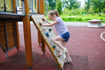 Adorable preschooler girl on playground on a sunny summer day. Preschooler child playing outdoors....