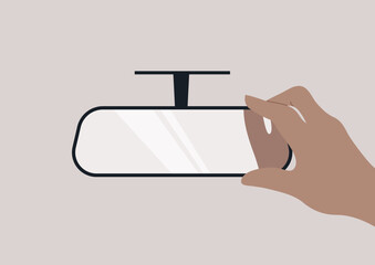 A hand reaches toward a rear view mirror, positioning it for optimum reflection, It captures the intention to ensure safety and awareness on the road ahead