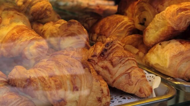 Delicious golden croissants and other pastries displayed in a bakery window in Paris, ready to be enjoyed