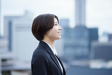 スーツを着た若い日本人女性と都会の街並み