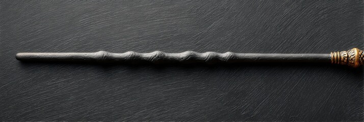 Dark, ornate wand rests on a black surface.  Mysterious and magical.