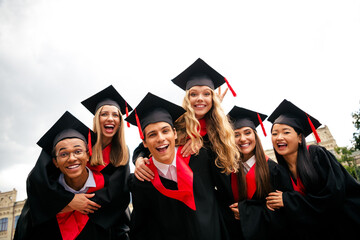 Joyous group of graduates in caps and gowns celebrating outdoors on a summer day
