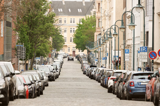 Scenic view Magdeburg Altstadt Leibniz street modern cars covered parked row roadside sunny summer day. Sidewalk parallel side parking full of vehicles traffic jam in downtown