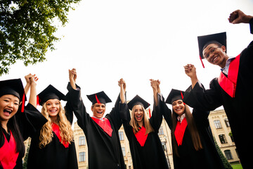 Happy group of young graduates celebrating their college success outdoors on campus