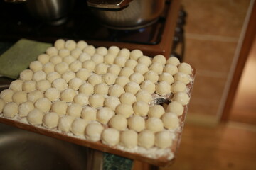 Homemade dumplings or vareniki on a mold, ready for boiling. Cozy kitchen atmosphere, traditional cooking, warmth and comfort of homemade food.