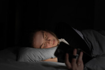 Peaceful nighttime moment with a woman asleep, holding a phone loosely in her hand. The scene shows...