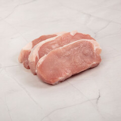 Fresh pork loin chops stacked on white marble surface ready for cooking – High Resolution Raw Meat Image for Food Industry or Food Packaging