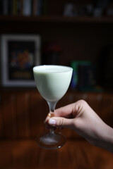 Hand holding grasshopper cocktail served in a classic martini glass, close-up