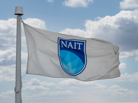 Edmonton, Alberta, Canada. May 19, 2025. The NAIT flag proudly waves against a dynamic sky, embodying the spirit of innovation and technical education in Alberta.