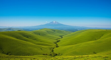 Obraz premium Rolling green hills meet majestic mountain peak