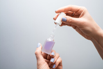 A woman holds an open jar of cuticle oil, showing the product and brush in close-up