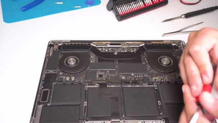 Expert technician repairs laptop components in a well-equipped workshop with precision tools and techniques