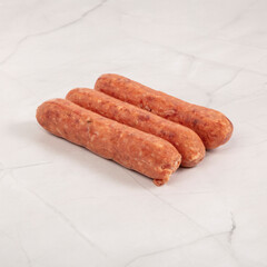 Three fresh italian sausages on a white marble surface close up – High Resolution Raw Meat Image for Food Industry or Food Packaging