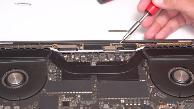 Expert technician repairs notebook computer in workshop, showcasing detailed maintenance techniques and precision in every step