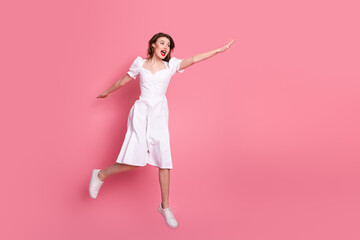 Young lovely woman in elegant white dress making a cheerful pose on a vibrant pink background
