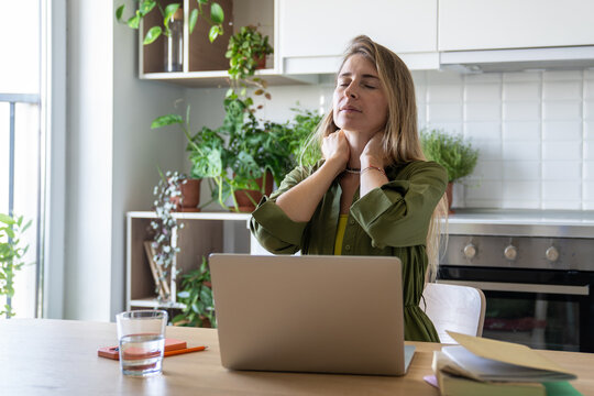 Tired female sitting at table with laptop have exhausted from intense work. Unwell woman closed eyes, feeling pain trying to relax neck after sitting in one position. Break to recuperate avoid fatigue