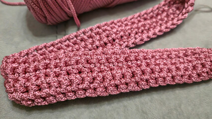 Knitting elements of a pink women's bag, hand knitting with a long handle.