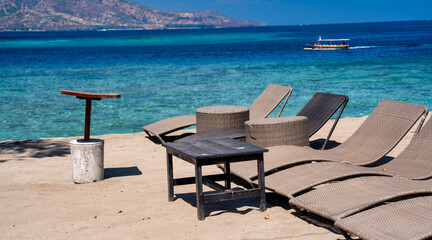 Tropical beach with gray lounge chairs for relaxation under the sun