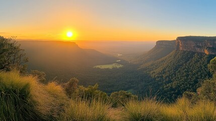Fototapeta premium A scenic landscape of a valley and mountains at sunset with a golden glow.