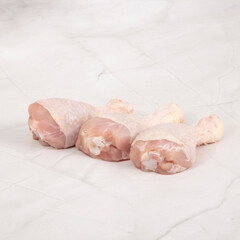 Fresh raw chicken drumsticks on white marble surface preparation for cooking – High Resolution Raw Meat Image for Food Industry or Food Packaging