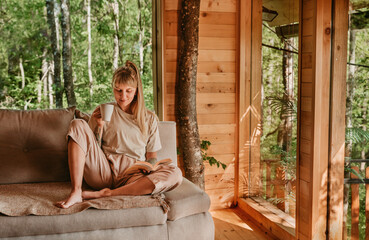 Woman Relaxing in Log Cabin with Tea and Book
