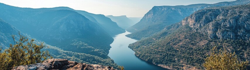 Obraz premium A sweeping panoramic view reveals a majestic river winding through towering mountain ranges.