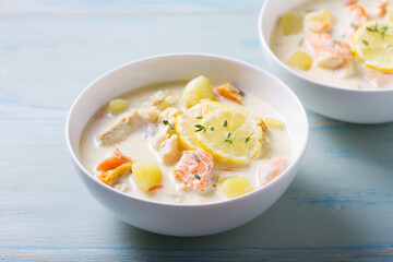 Fish and shrimp cream soup in white bowls on blue table