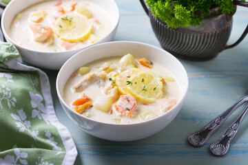 Fish and shrimp cream soup in white bowls on blue table