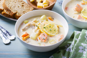 Fish and shrimp cream soup in white bowls on blue table