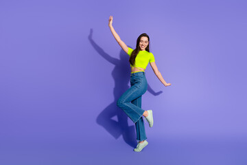 Young woman wearing casual fashion strikes a playful pose on a vibrant violet background, reflecting joy and modern summer style vibes