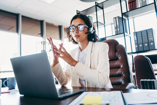 Confident businesswoman wearing formal attire in a modern office, engaging in a professional video conference