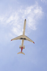 Low angle view of a commercial airplane flying overhead against a clear blue sky. The image captures the aircraft in motion, symbolizing travel, aviation, and modern air transportation.