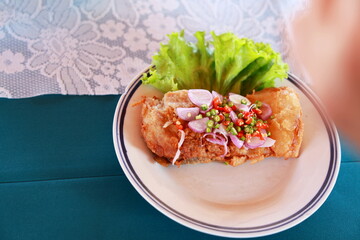 Sour fish served with spicy salad : Thai Spicy fermented fish with herbs deep-fry until crispy and add sliced ​​shallots, chopped chili peppers, green salad. Squeeze lemon juice. spicy fermented fish.
