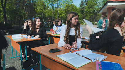 Students from high school and university are collaborating outdoors, exchanging notes and appreciating the outdoors