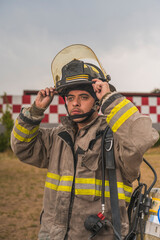 Naklejka premium Brave firefighter of Sapanish origin putting on and adjusting his helmet, ready to go put out a fire.