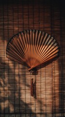 Elegant wooden fan casting warm shadows against a woven backdrop in tranquil ambiance