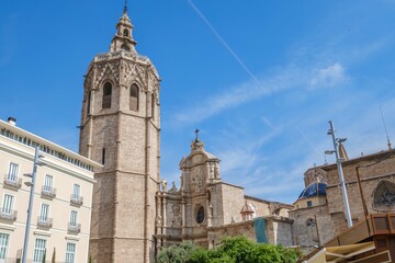 Valencia Cathedral and its iconic El Micalet bell tower rise above surrounding historic and contemporary buildings. This cityscape captures the blend of ancient architecture and urban life