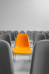 Fototapeta premium Bright orange chair stands out among gray seats in a minimalistic modern setting