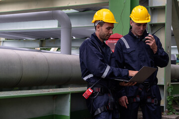 Workers collaborate on equipment inspection at an industrial plant during daylight hours