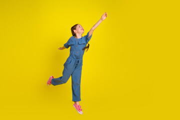 Obraz premium Preteen girl in fashionable blue outfit posing on vibrant yellow background showcasing happy and lively personality