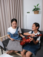 Two young girls are playing the violin together